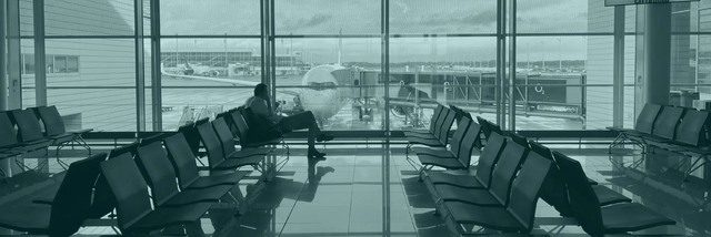 This image shows a business man at an airport gate with an Airbus A350 airplane in the background.