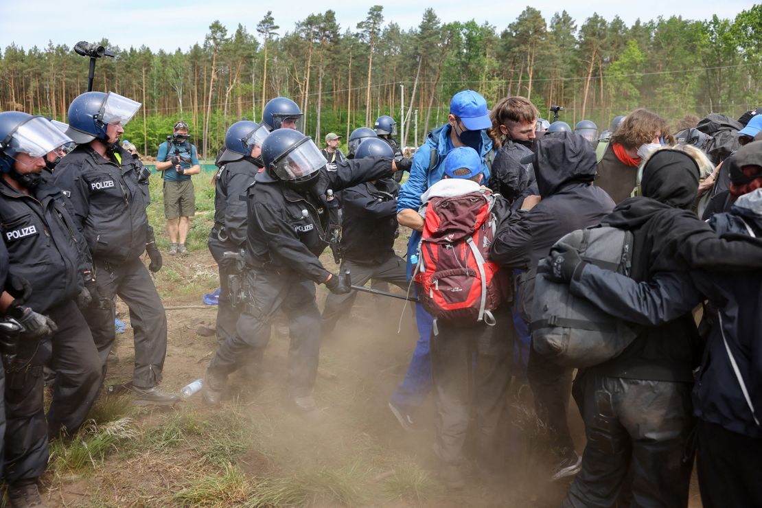 A police officer tries to push back protesters running toward the Tesla factory near Berlin on May 10, 2024.